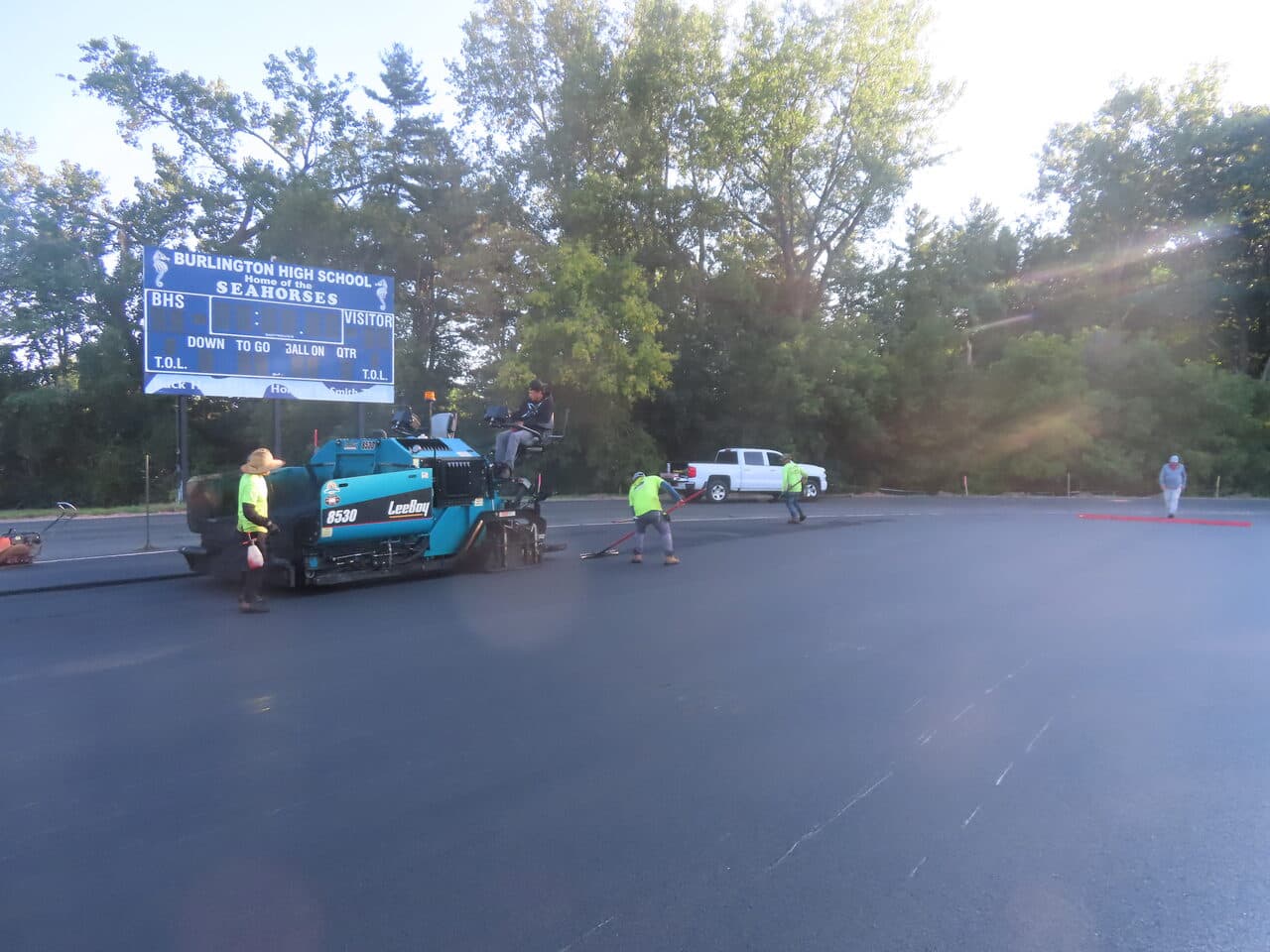 Athletic Surface Base Paving project in Burlington, VT — paver crew at scoreboard
