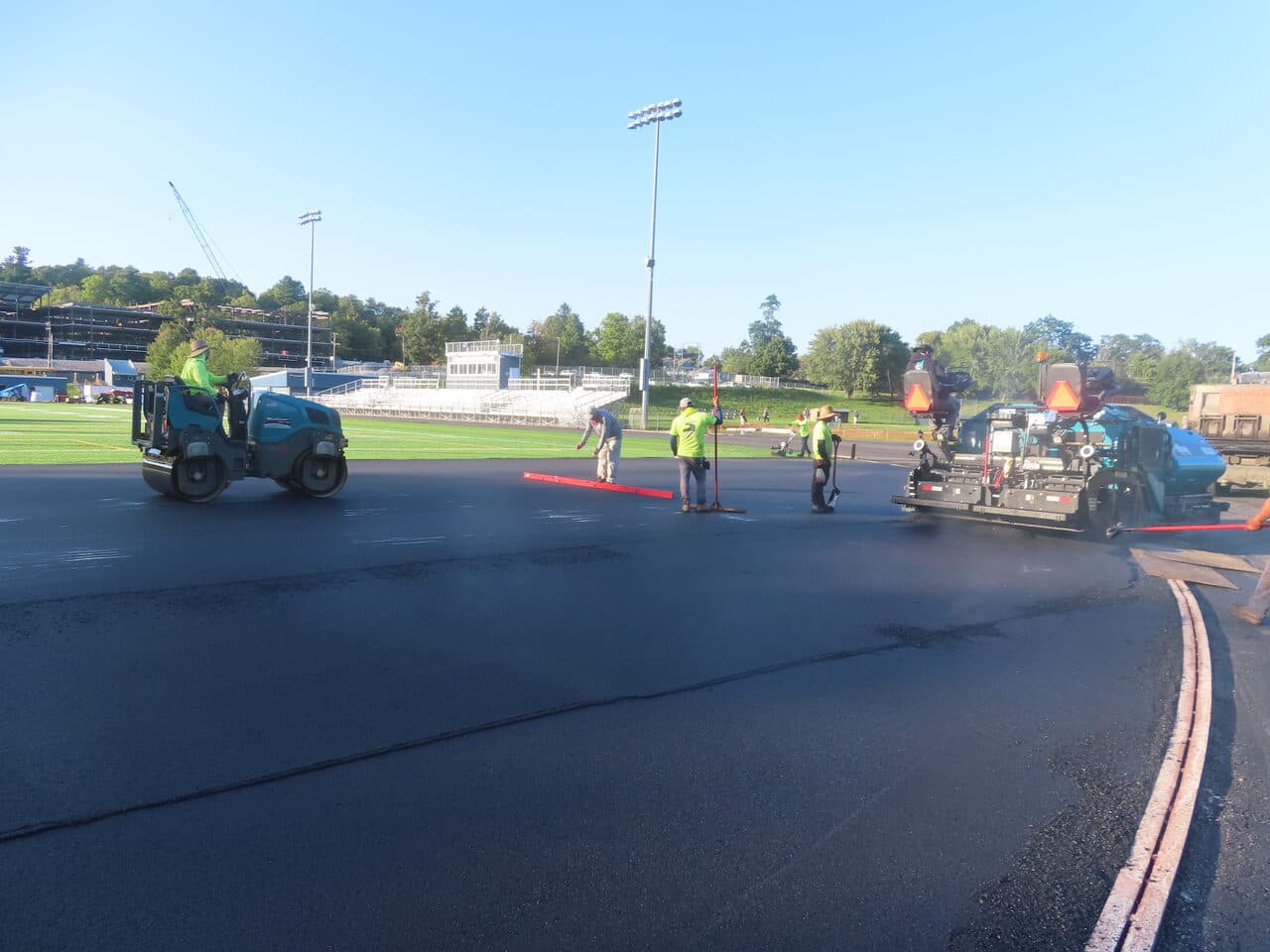 Athletic Surface Base Paving project in Burlington, VT — paver and roller on wide track