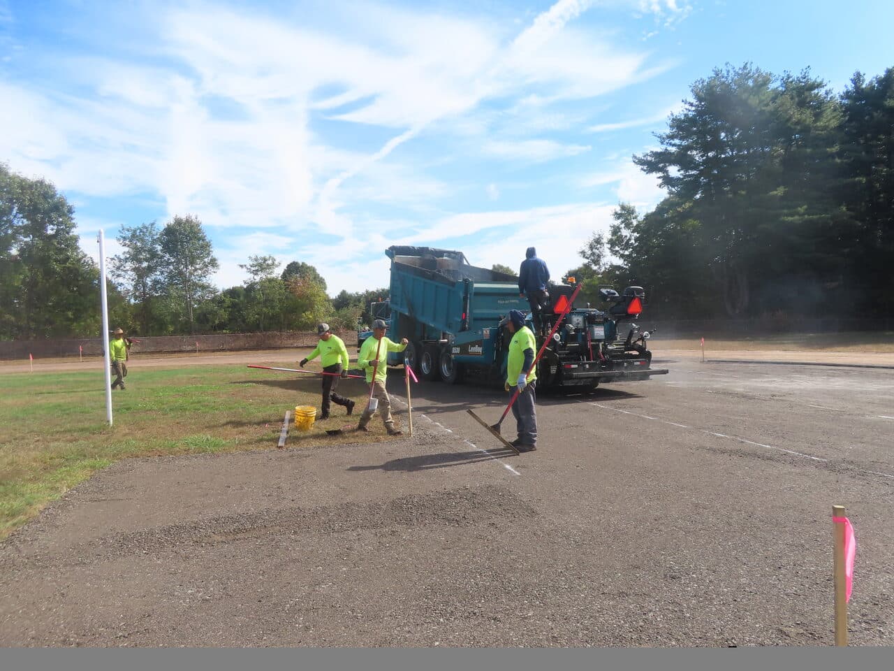 Athletic Surface Base Paving project in East Windsor, CT — crew raking edge near paver