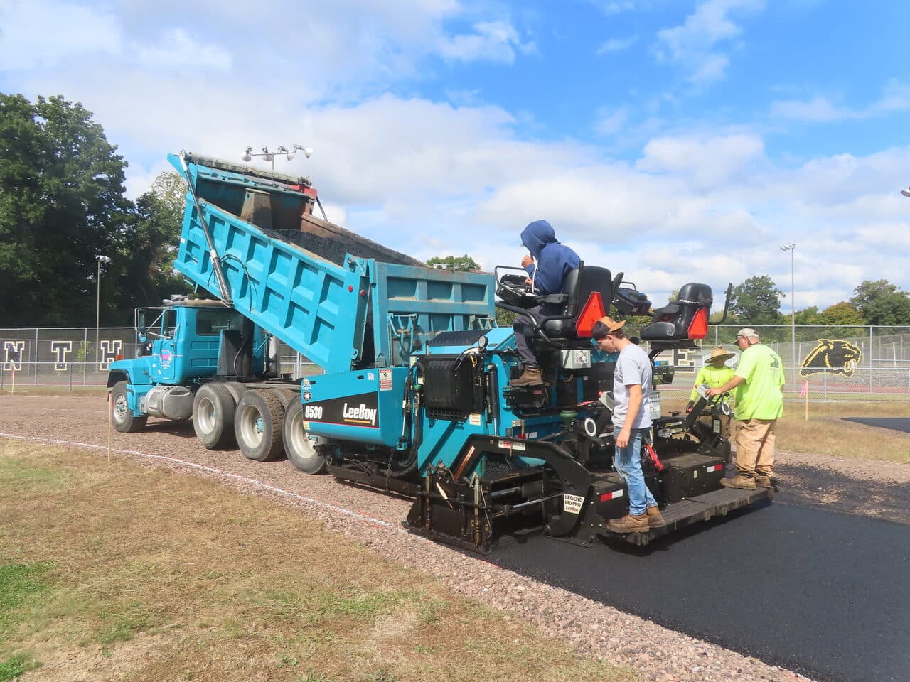 Athletic Surface Base Paving project in East Windsor, CT — paver and dump truck at track