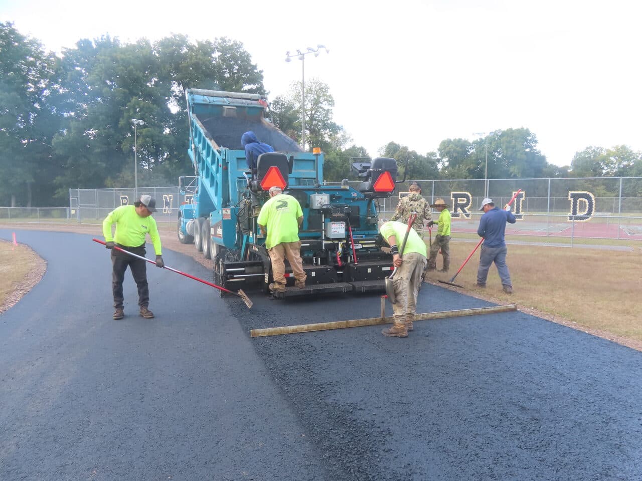 Athletic Surface Base Paving project in East Windsor, CT — crew paving track with rakes