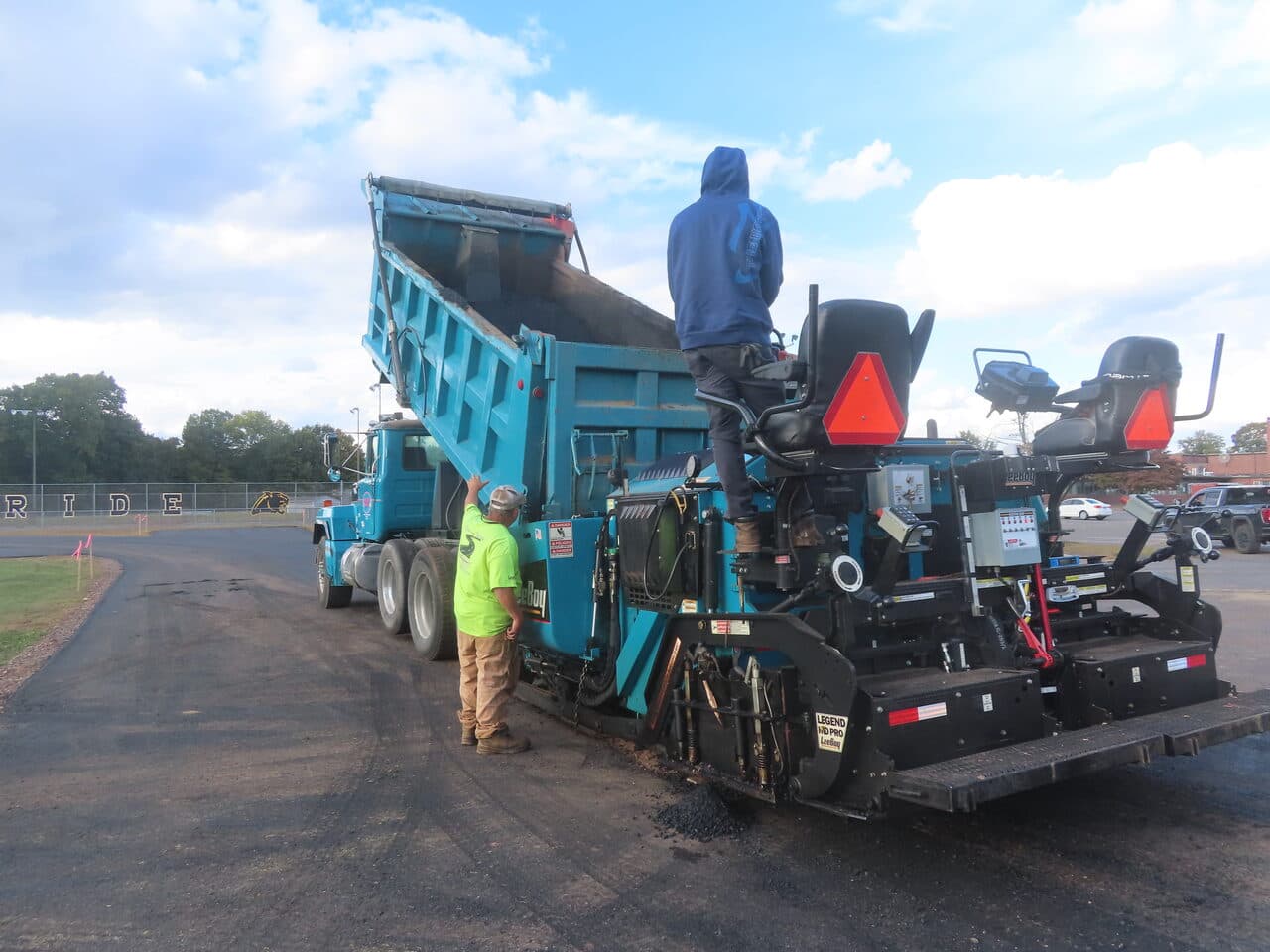 Athletic Surface Base Paving project in East Windsor, CT — worker watching truck load paver
