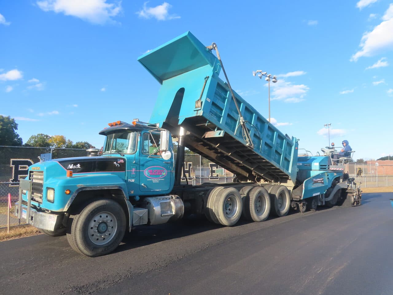 Athletic Surface Base Paving project in East Windsor, CT — Mack dump truck dumping into paver