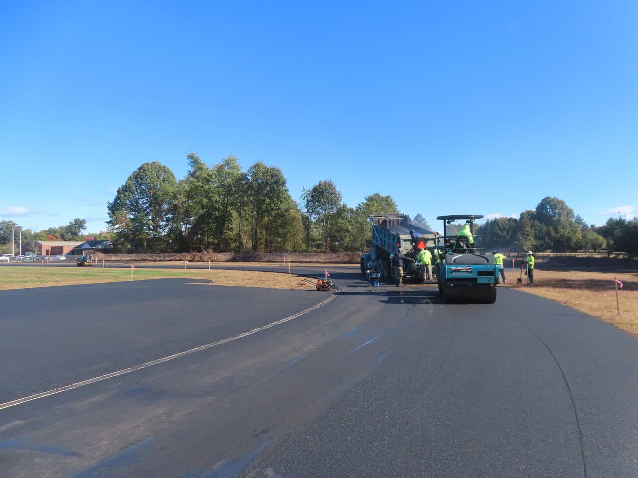 Athletic Surface Base Paving project in East Windsor, CT — roller and crew paving curved track