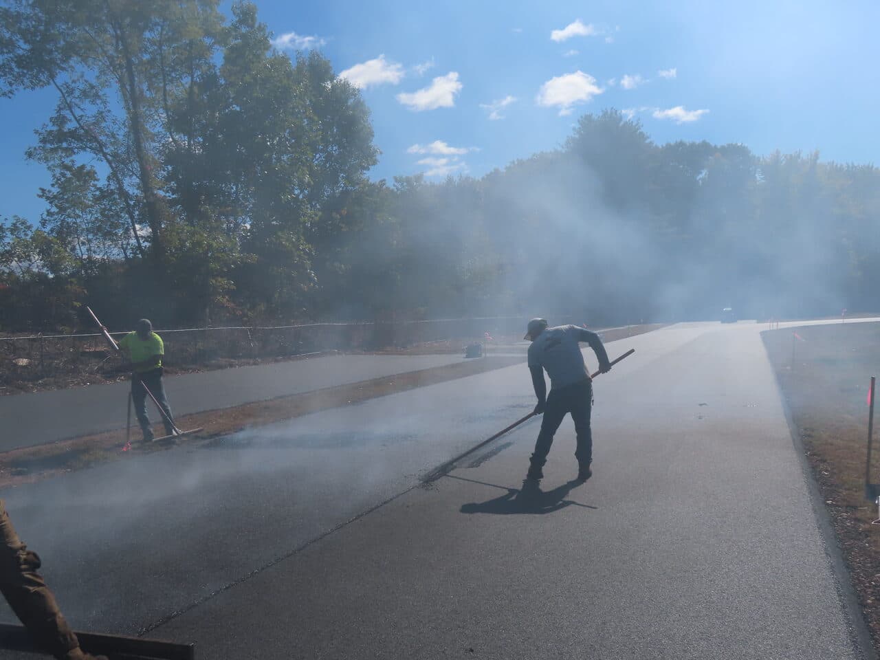 Athletic Surface Base Paving project in East Windsor, CT — workers raking fresh asphalt in steam