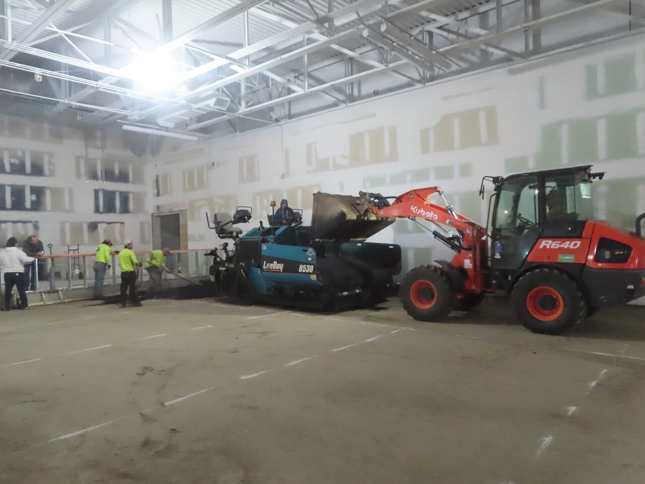 Commercial Parking Lot Paving project in Newport, RI — paver and loader staged indoors with crew