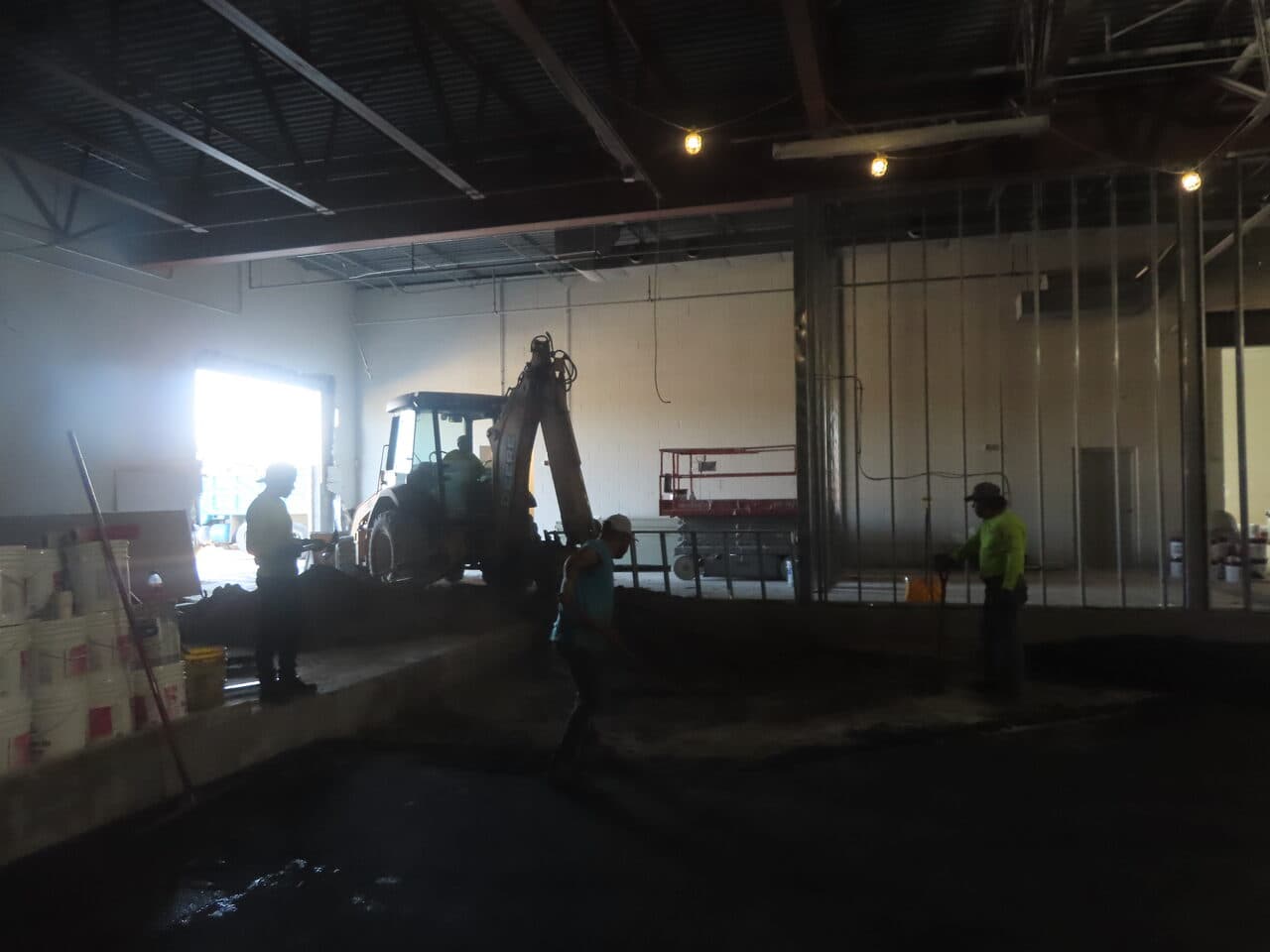 Commercial Parking Lot Paving project in Newport, RI — crew and backhoe spreading asphalt indoors