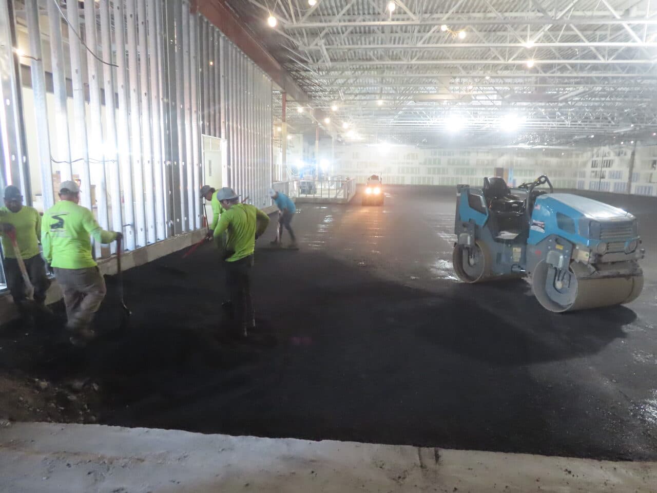 Commercial Parking Lot Paving project in Newport, RI — crew raking with roller compacting indoors