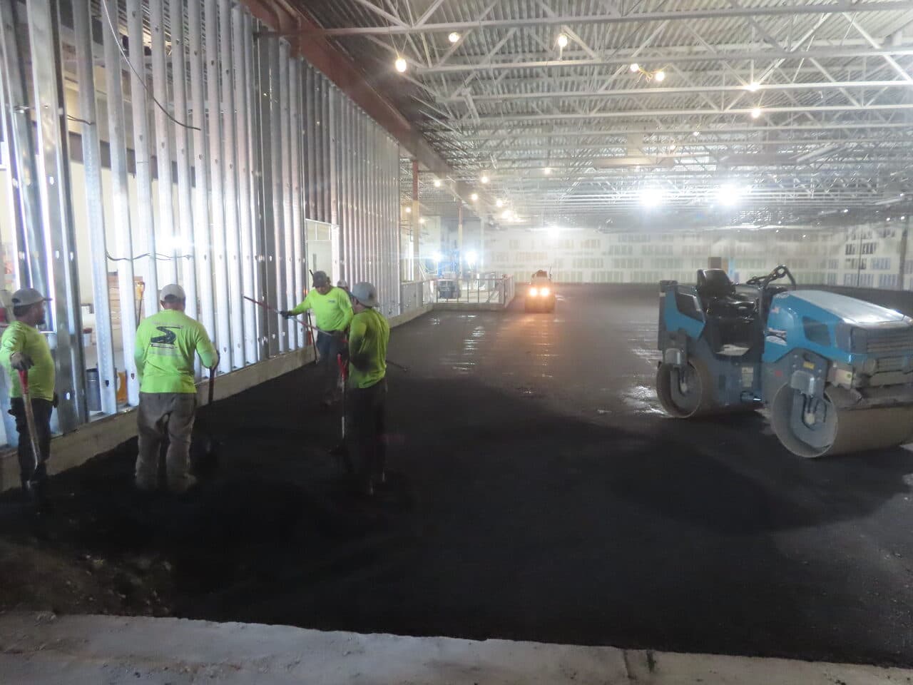 Commercial Parking Lot Paving project in Newport, RI — crew raking with roller compacting indoors