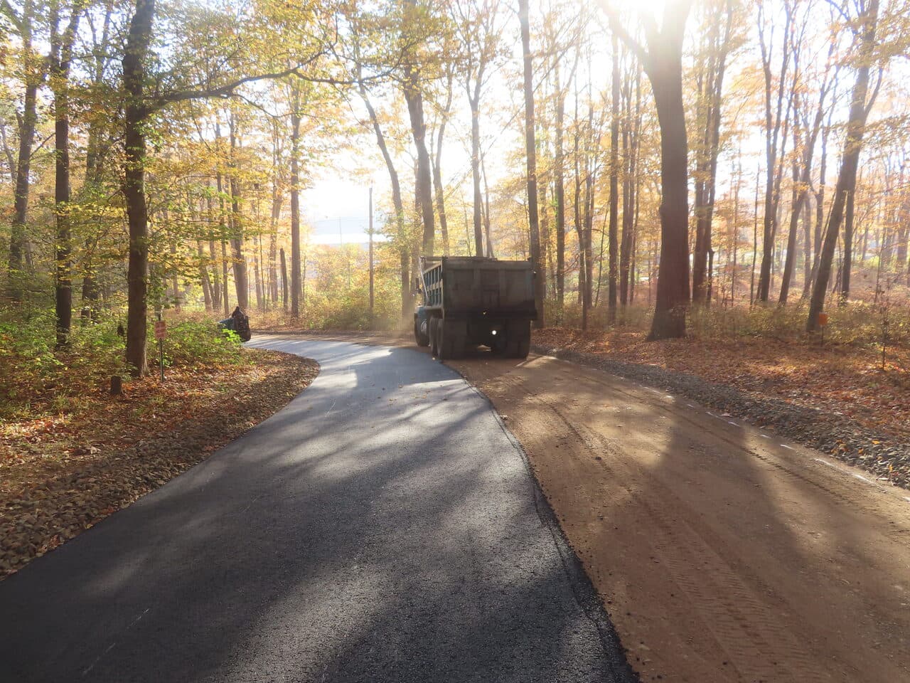 Roadway Paving project in Wallingford, CT — finished new road through autumn woods