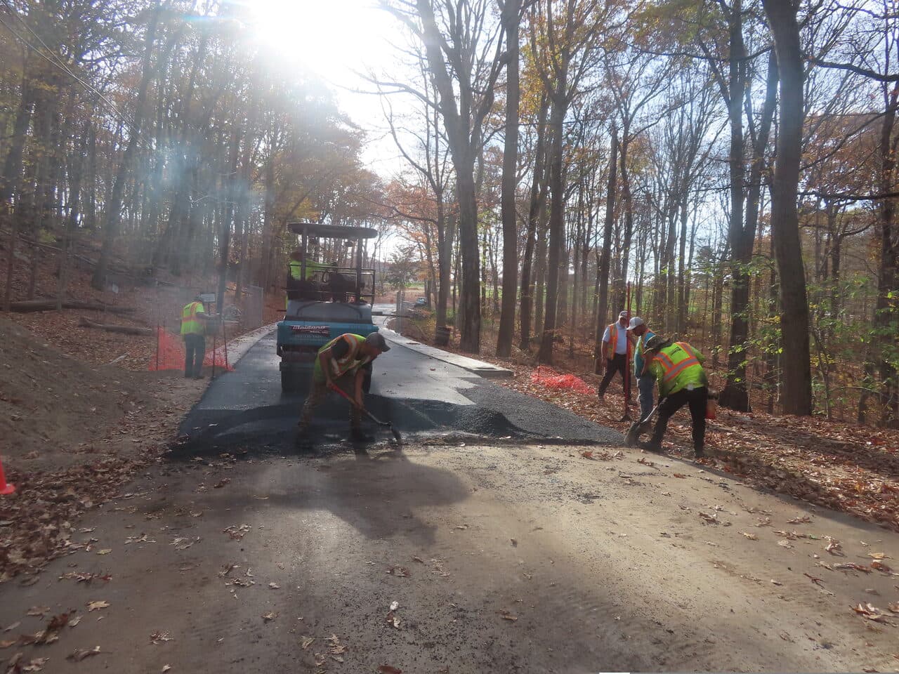 Golf Course Paving project in New Haven, CT — crew hand-raking asphalt wooded path