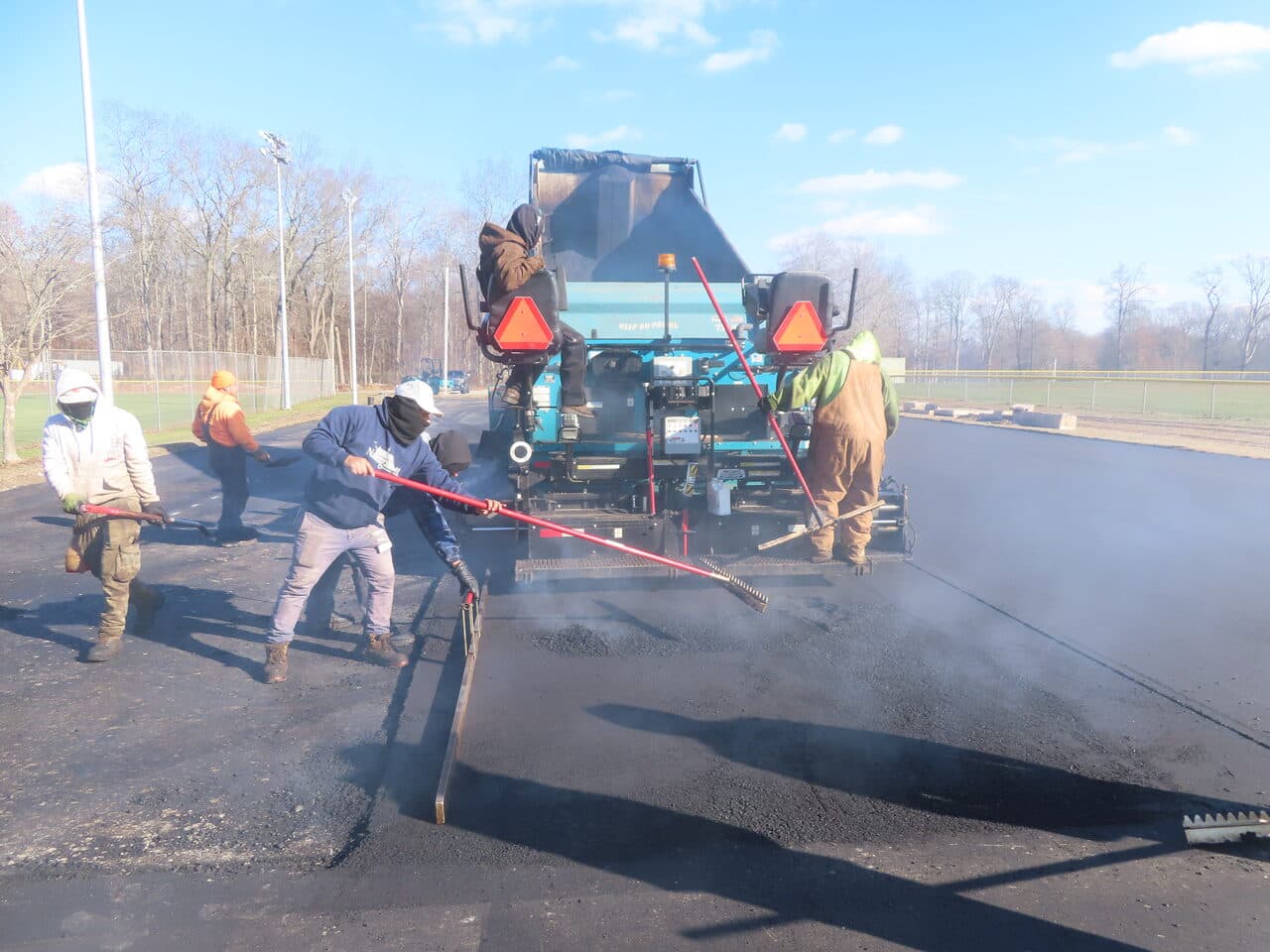 Commercial Parking Lot Paving project in Montville, CT — crew raking hot mix at paver