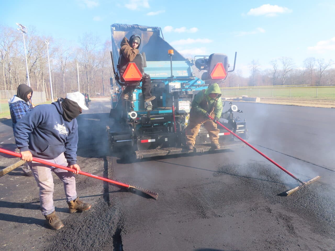 Commercial Parking Lot Paving project in Montville, CT — workers raking asphalt behind paver