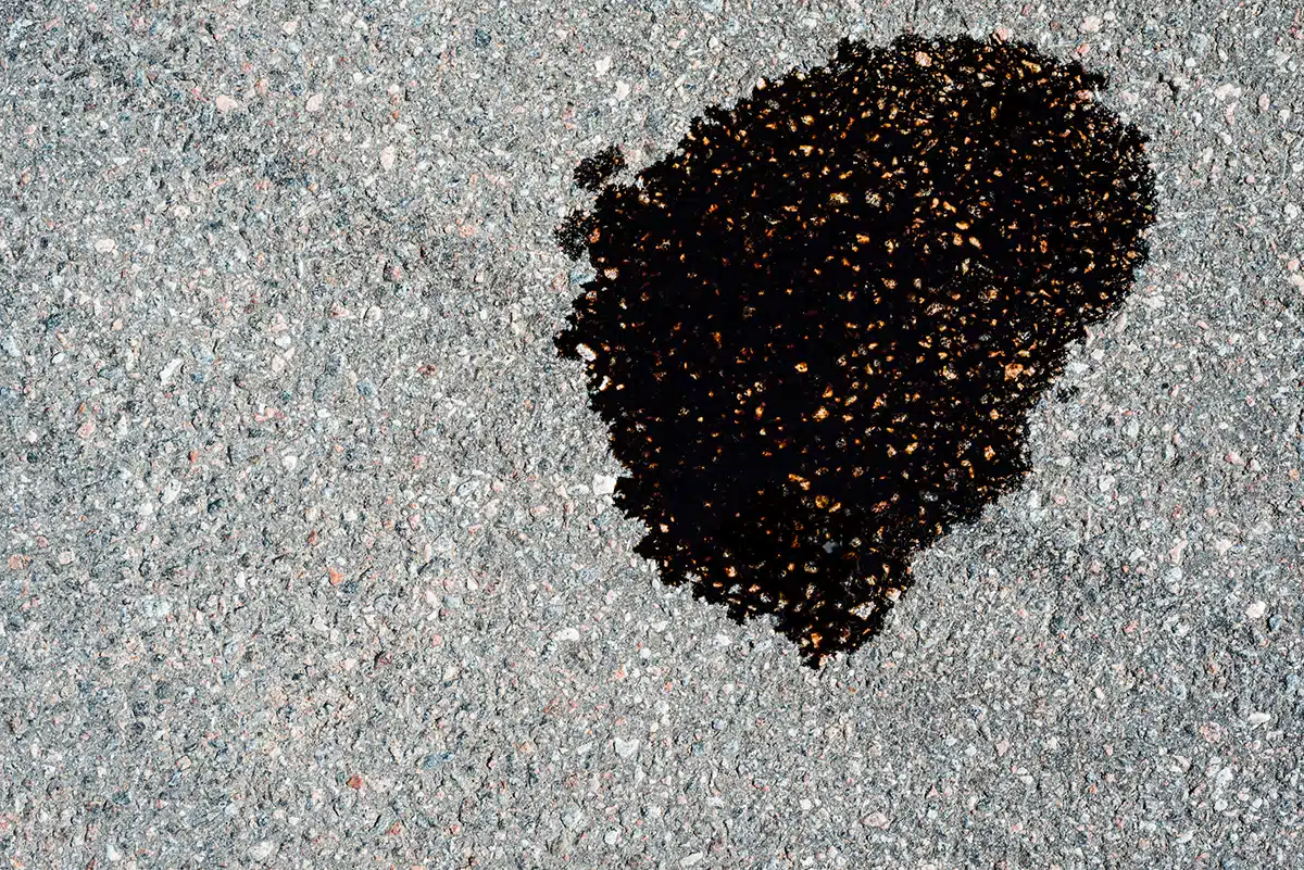 Oil puddle leak on asphalt driveway