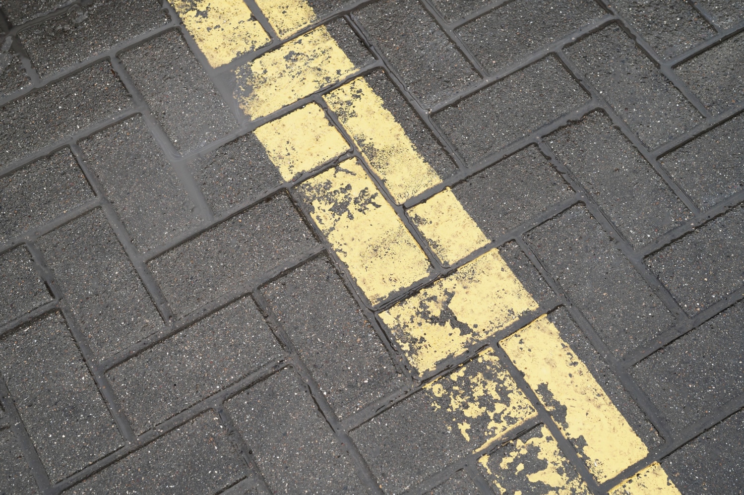Stamped asphalt pavement with yellow traffic striping and wet surface texture