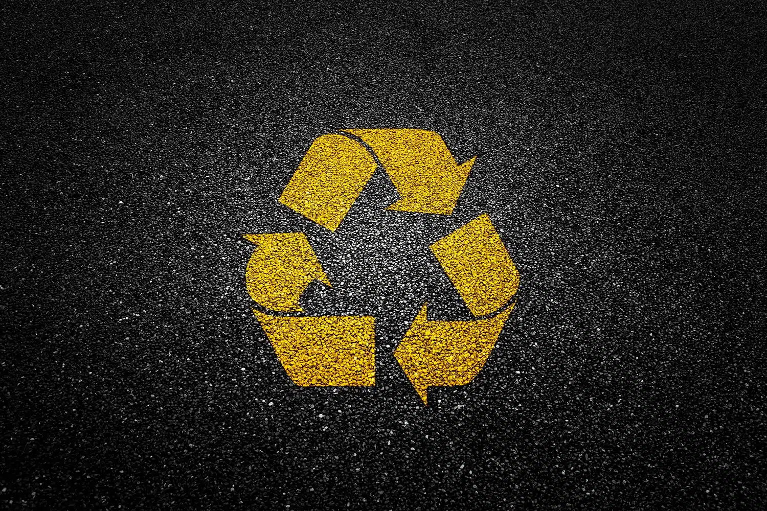 Yellow recycling symbol painted on asphalt pavement