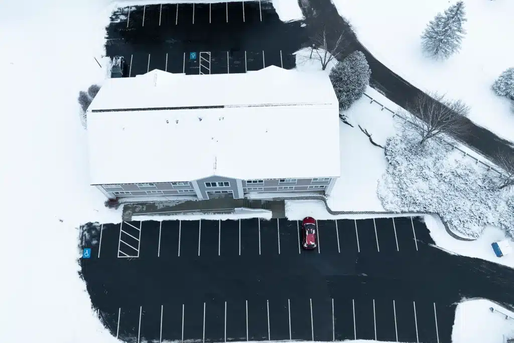 Aerial view of a commercial parking lot cleared of snow during winter.