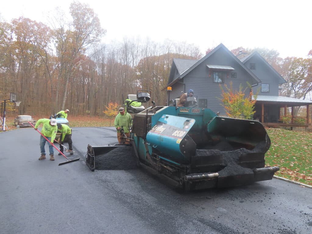 Asphalt paving crew installing a new residential driveway in Clinton, Connecticut using professional paving equipment