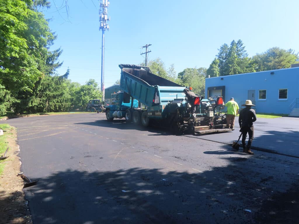 Commercial asphalt paving in progress in Killingworth, CT by Maisano Bros. Inc., with fresh pavement placement and crew finishing work onsite.